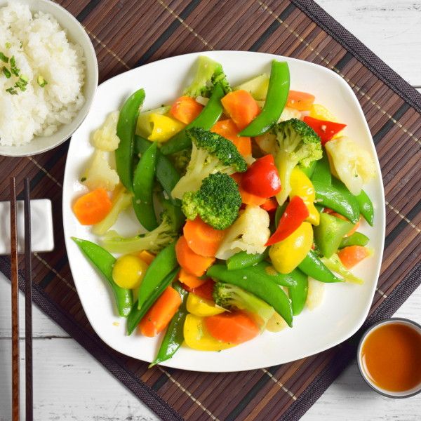 a white plate topped with veggies and rice next to a bowl of broccoli