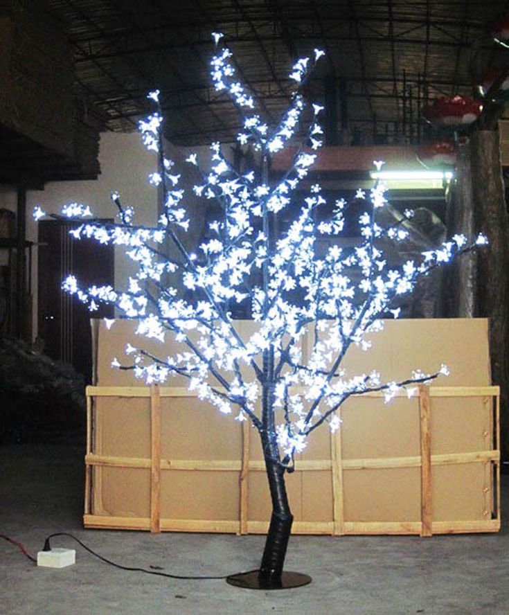 a small tree with white lights on it in the middle of a warehouse floored area