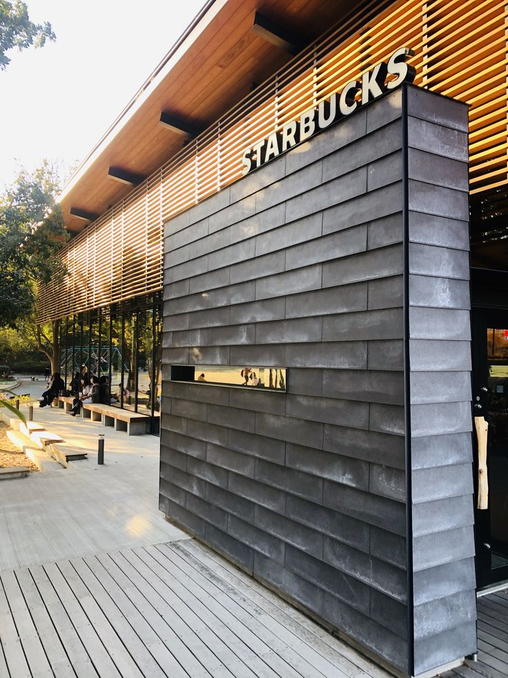 the outside of a store with wooden floors and large black building that says starbuck's