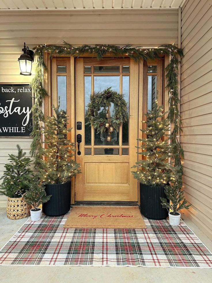 the front door is decorated with christmas wreaths and potted trees for holiday time