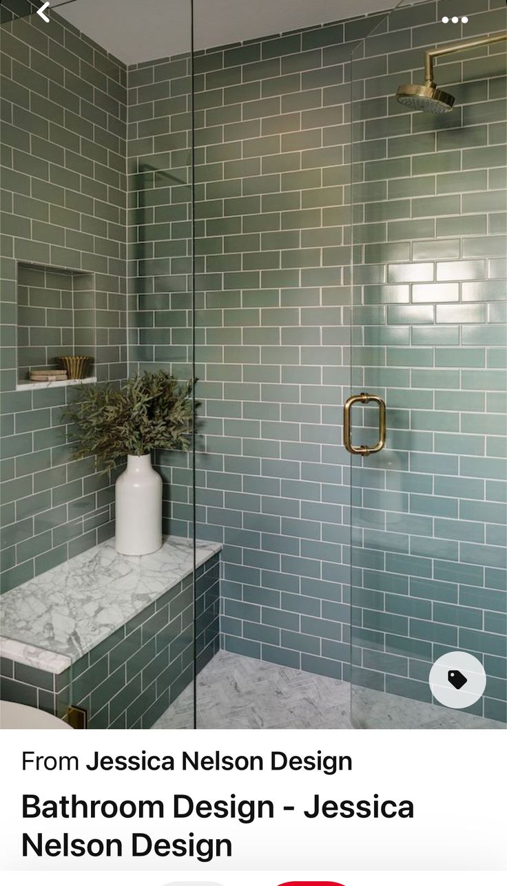 a bathroom with green tiles and a white vase on the counter next to the shower