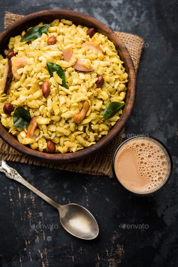 a wooden bowl filled with rice and nuts next to a cup of coffee on top of a