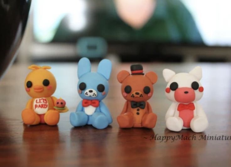 four small toy animals sitting on top of a wooden table