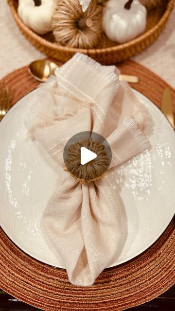 a white plate topped with a napkin next to a basket filled with pumpkins