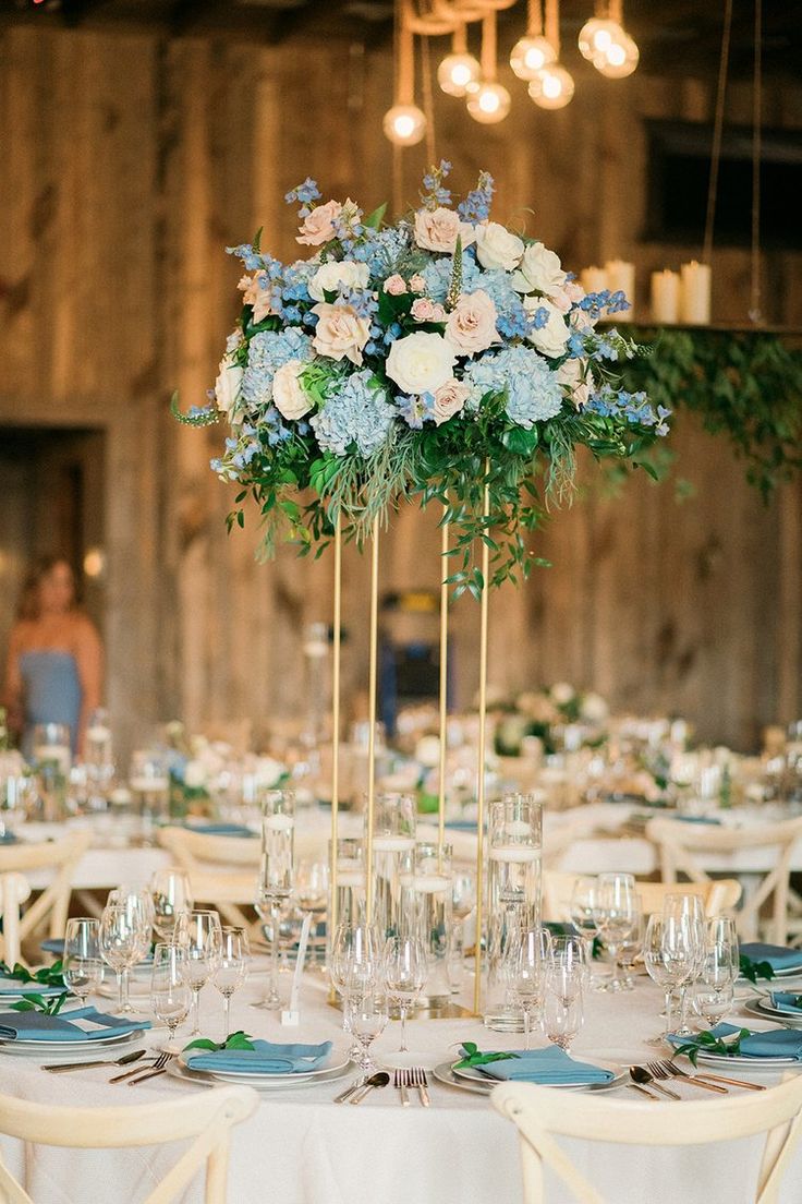 a tall vase filled with blue and white flowers on top of a dining room table