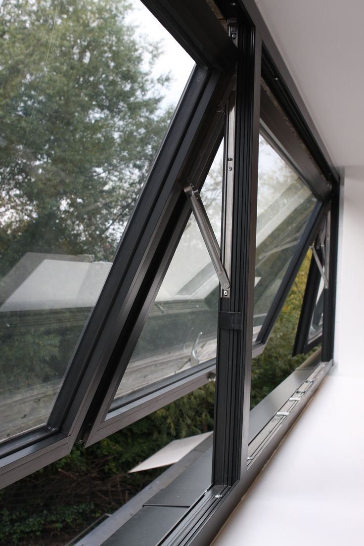 an open window on the side of a building with trees in the back ground below