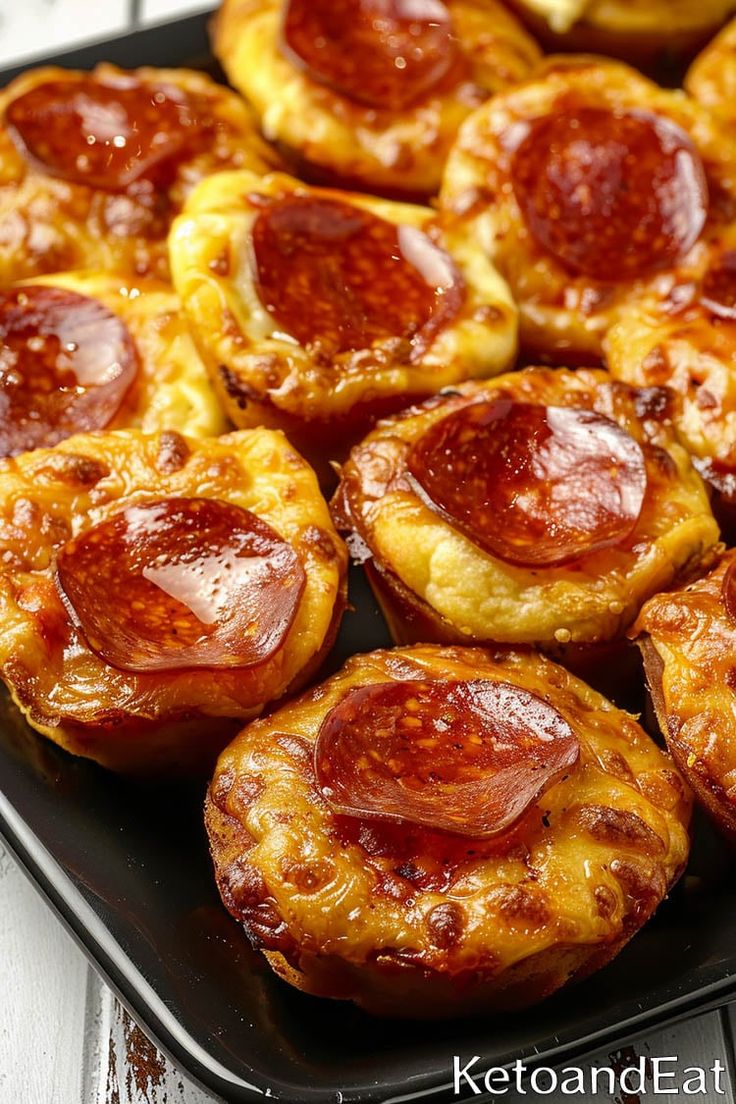 mini pizzas with pepperoni and cheese are on a black tray next to bananas