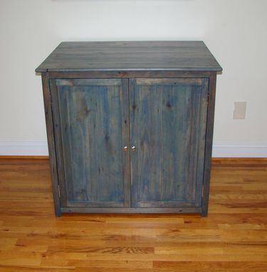 a wooden cabinet sitting on top of a hard wood floor next to a white wall