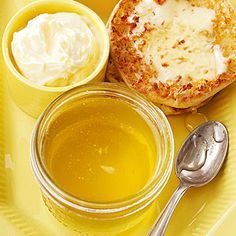 a yellow plate topped with food and a bowl of soup next to a cup of cream