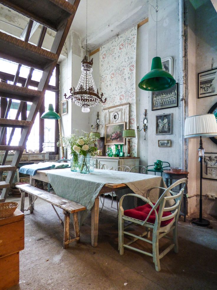 an old fashioned dining room with green lamps and pictures on the wall behind the table