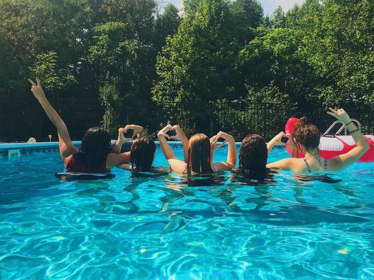 several people in a pool with their arms up