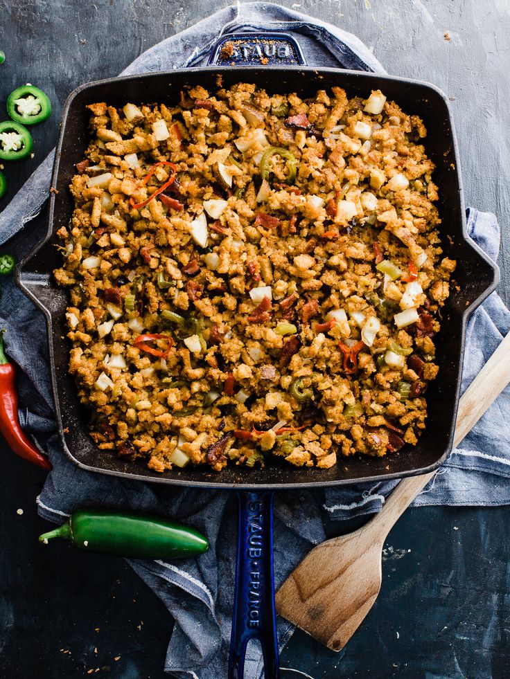 a casserole dish filled with vegetables on top of a blue cloth next to green peppers