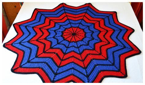 a red, white and blue crocheted blanket on top of a bed