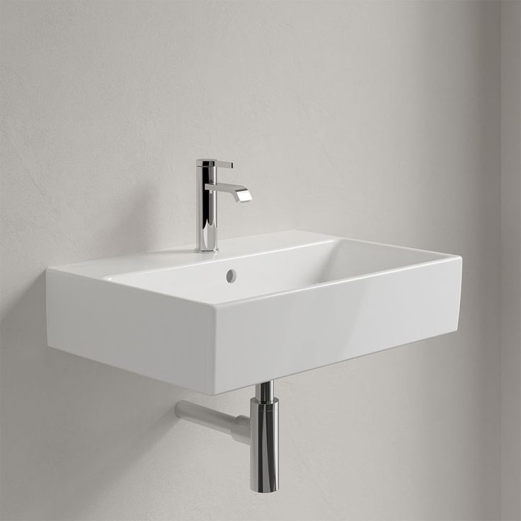 a white sink mounted to the side of a wall next to a faucet