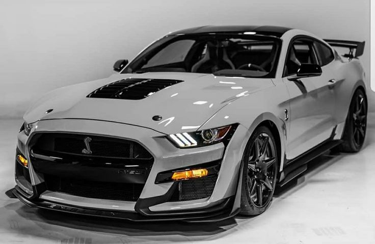 the front end of a silver sports car in a white room with black stripes on it