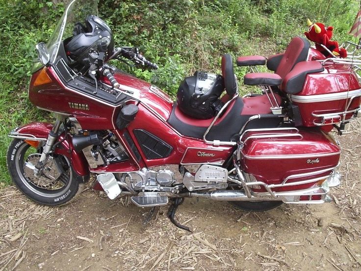 a red motorcycle parked on top of a dirt road