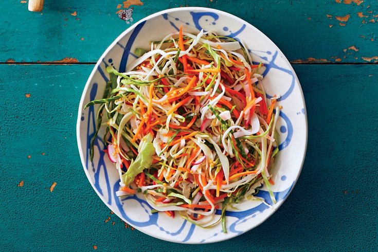 a white bowl filled with shredded carrots on top of a blue table