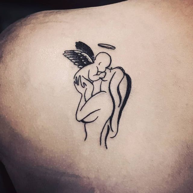 a tattoo on the back of a woman's shoulder with an angel holding a baby