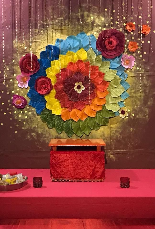 a vase filled with lots of colorful flowers on top of a red table covered in confetti