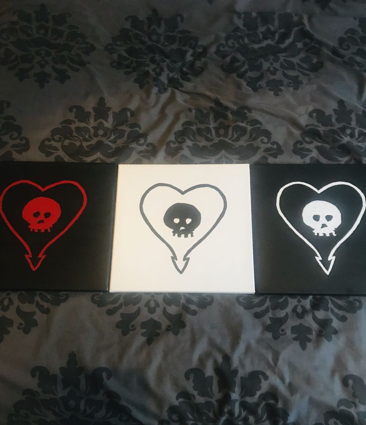 three heart shaped stickers with skulls in them on a black and white bed sheet