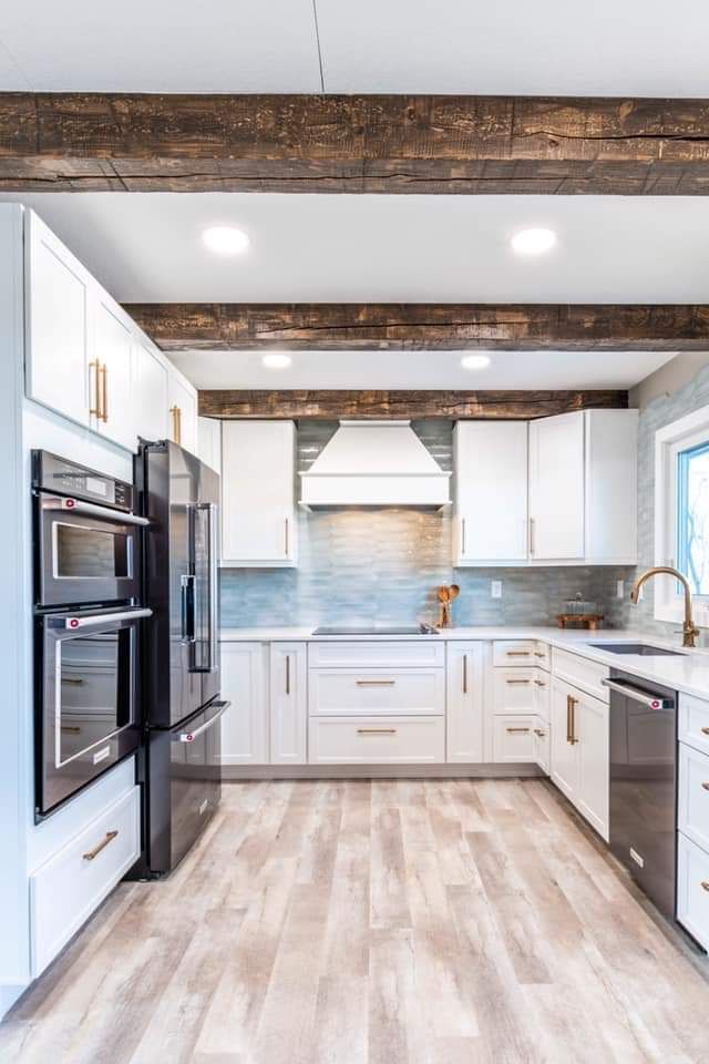 a kitchen with white cabinets and wood flooring, along with stainless steel ovens