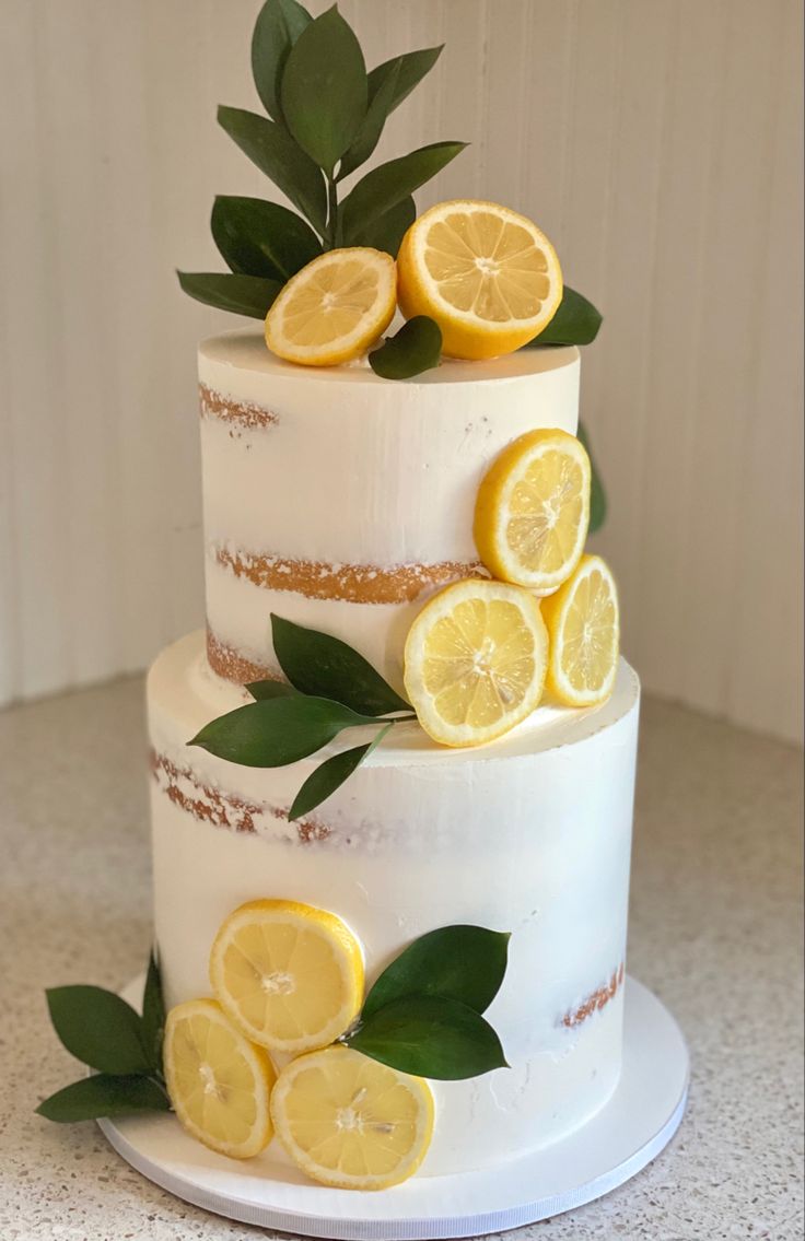 a three tiered cake with lemons and leaves on top