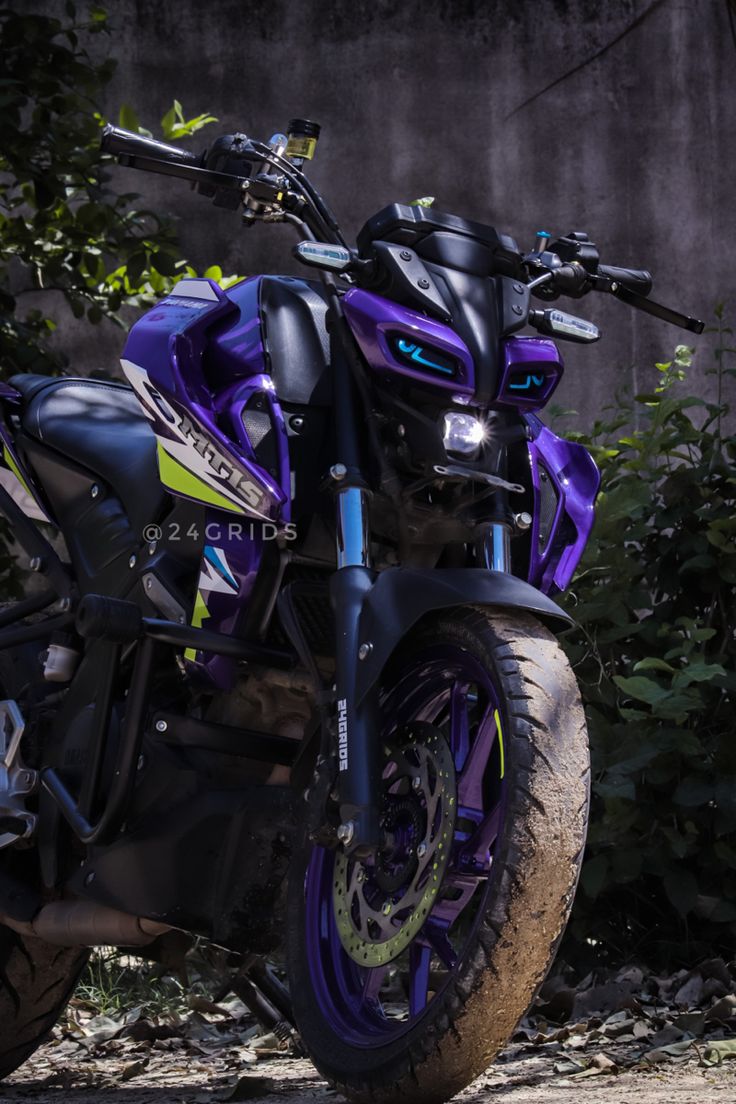 a purple and black motorcycle parked in front of some bushes