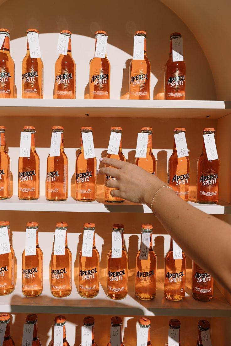 a person reaching for a bottle of peach soda on a shelf in front of other bottles