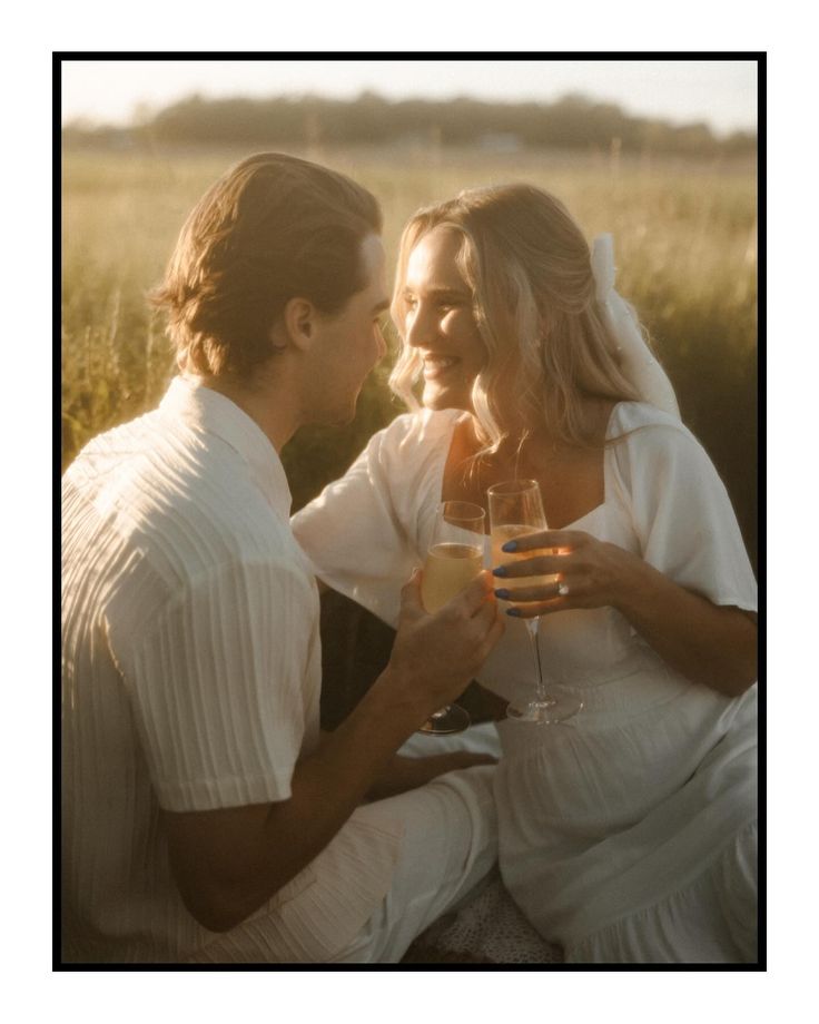 a man and woman sitting next to each other holding wine glasses