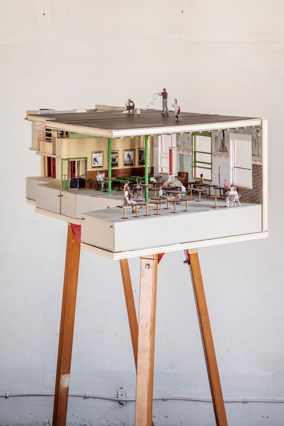 a model of a house on top of a table with people in the room inside