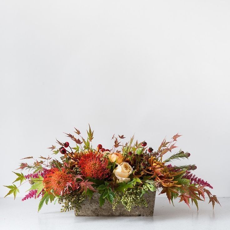 an arrangement of flowers and greenery in a wooden vase on a white background with space for text