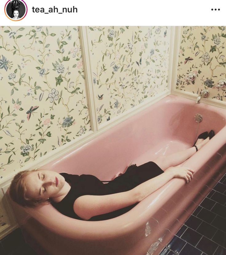 a woman laying in a pink bath tub