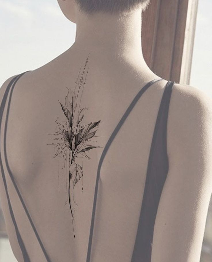 the back of a woman's body with a flower tattoo on her left side