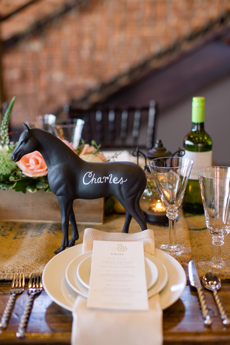 a black horse figurine sitting on top of a table next to plates and glasses