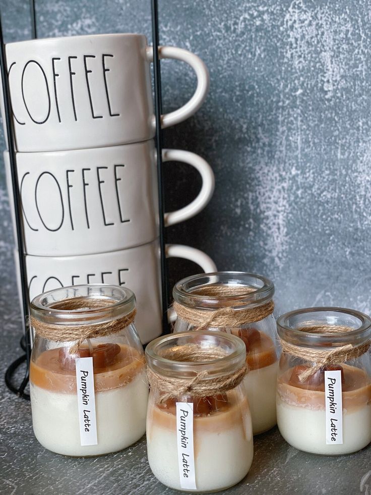 four jars filled with different types of food next to a coffee mug and sign on the wall