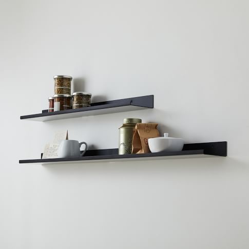 two black shelves with coffee cups and other items on them against a white wall in a kitchen