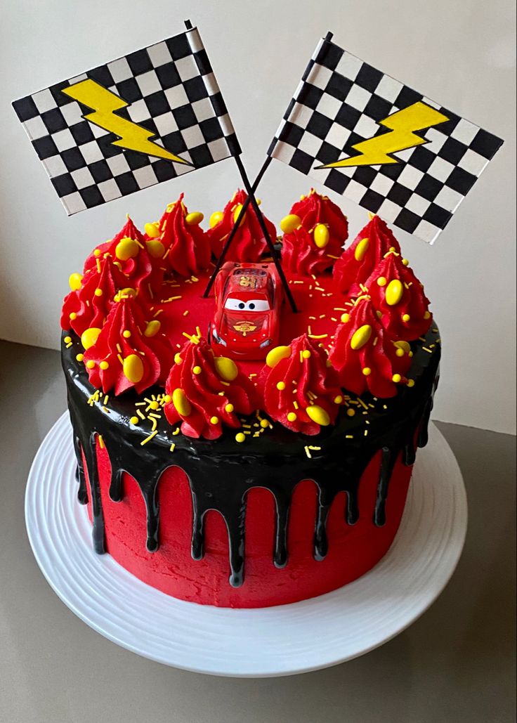 the cake is decorated with red icing and has cars on it, along with two checkered flags