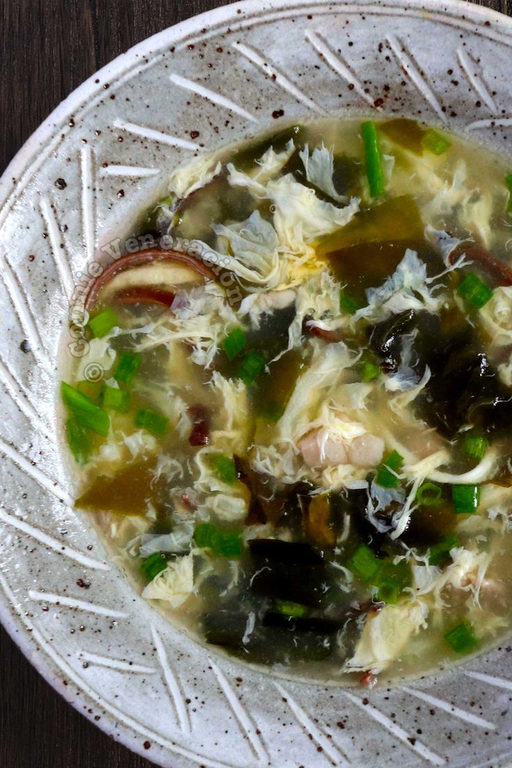 a white bowl filled with soup on top of a wooden table