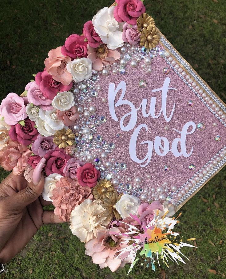 someone holding up a pink and white graduation cap with the words but god written on it