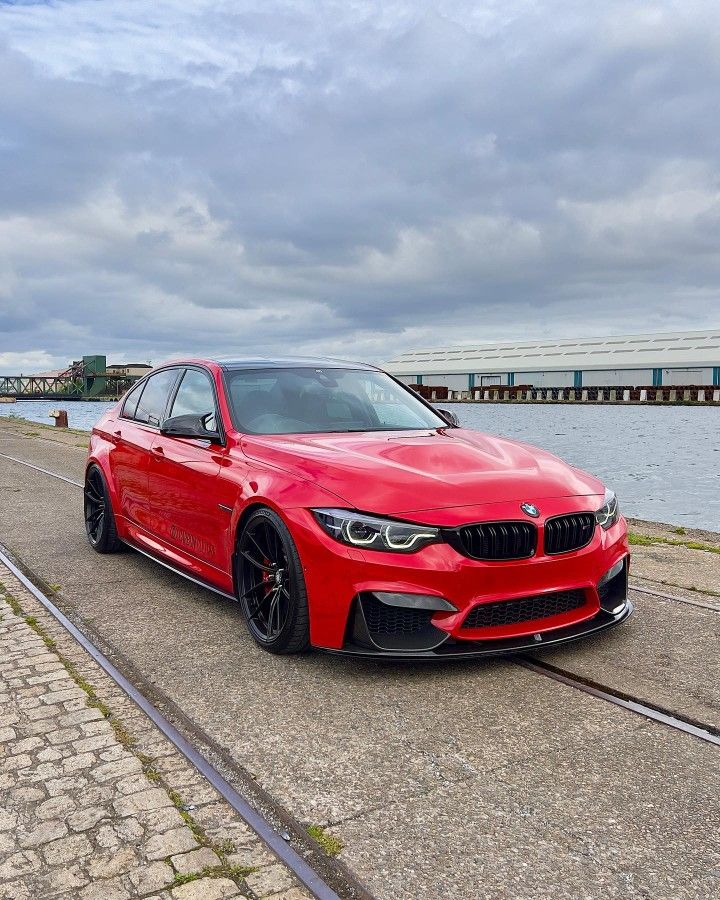 a red car parked on the side of a road next to a body of water