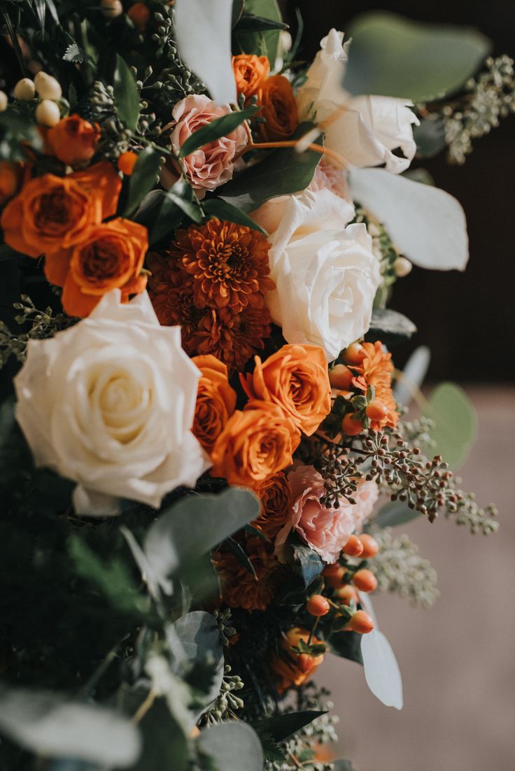 an orange and white bouquet with greenery