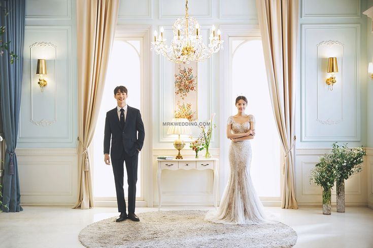 a man and woman standing in front of a chandelier