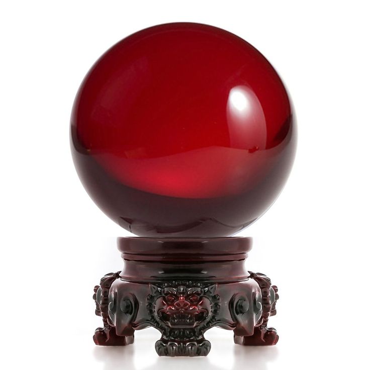 a red glass ball sitting on top of a wooden stand in front of a white background