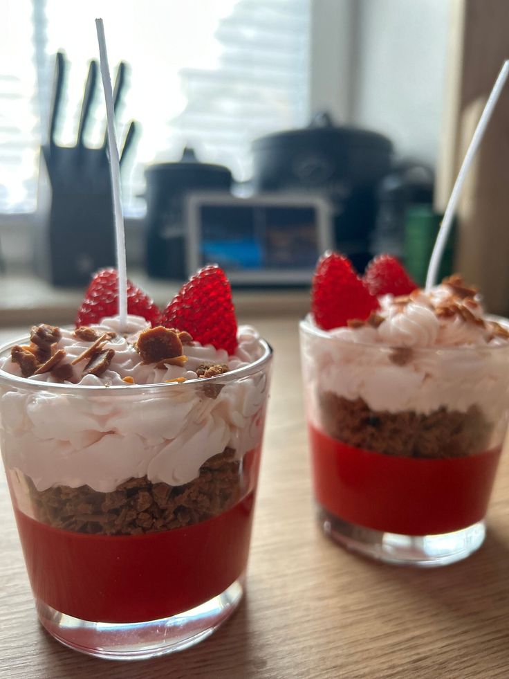 two desserts with strawberries and whipped cream on top are sitting on a table