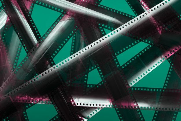 an abstract photograph of film strips in pink and green tones on a teal background