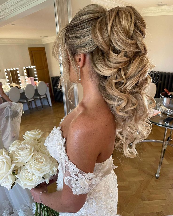 a woman in a wedding dress is holding flowers and looking down at the floor with her back to the camera