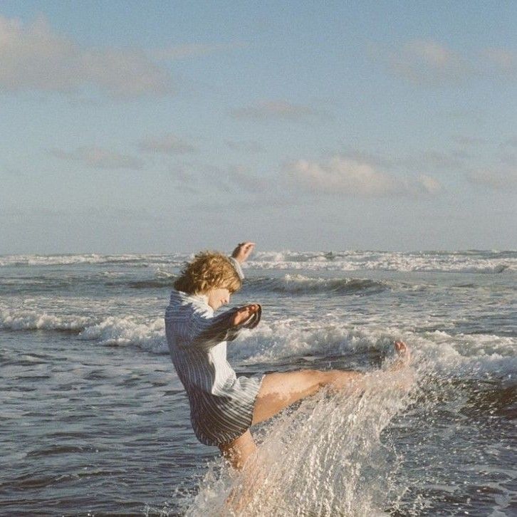 a young man riding a surfboard on top of a wave in the ocean,