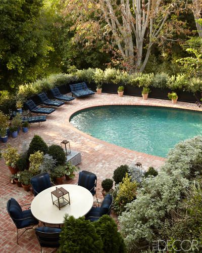 an aerial view of a swimming pool and patio with lounge chairs around it, surrounded by trees