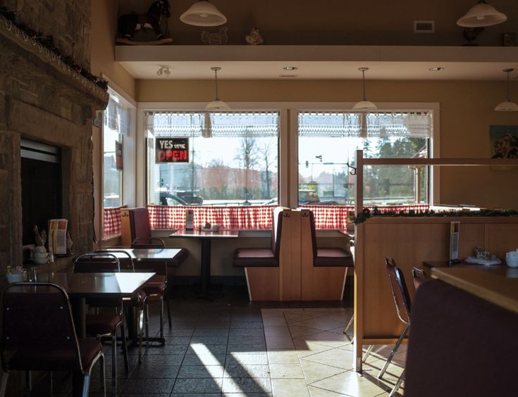 the interior of a restaurant with tables, chairs and windows looking out onto the street