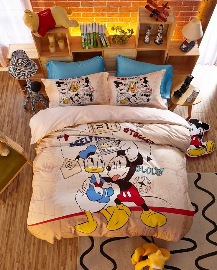 a bed with mickey mouse comforter and pillows